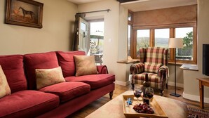A living room with a red sofa, a plaid armchair, and a wooden coffee table with a tray of grapes and wine glasses. - HEATHERDENE - Cottage set in the midst of the Yorkshire Dales with amazing views (Richmond)
