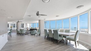 A spacious dining area with a high ceiling and large windows offering a view of the ocean.