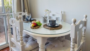 Ett runt glasbord med vita stolar, en glasskiva som bordsskiva och en vävd bordstablett.