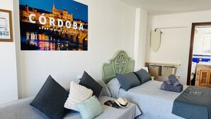 Ett hotellrum med två sängar, ett nattduksbord, en spegel och en affisch av Córdoba.