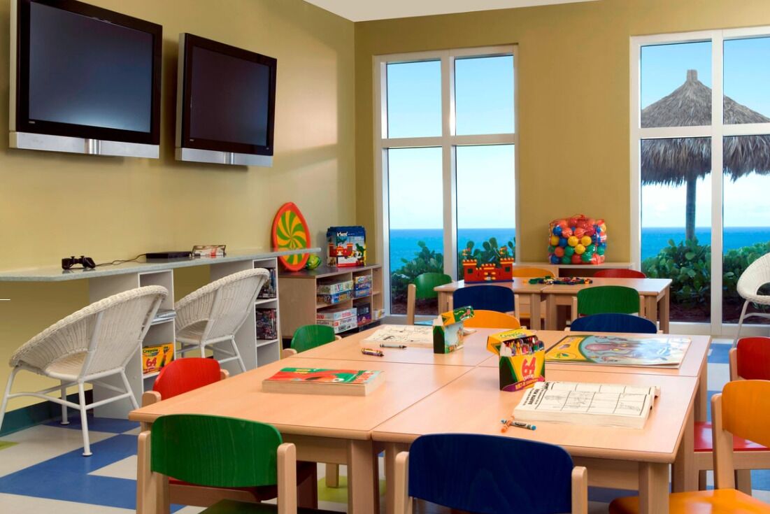 A children's playroom with tables, chairs, and educational toys.