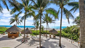 A beachside resort with thatched-roof huts, lounge chairs, and a view of the ocean. - Singer Island Palm Beach Marriott: 2 BDRM/2 BATH Condo +Resort Access 14th Floor (Riviera Beach)