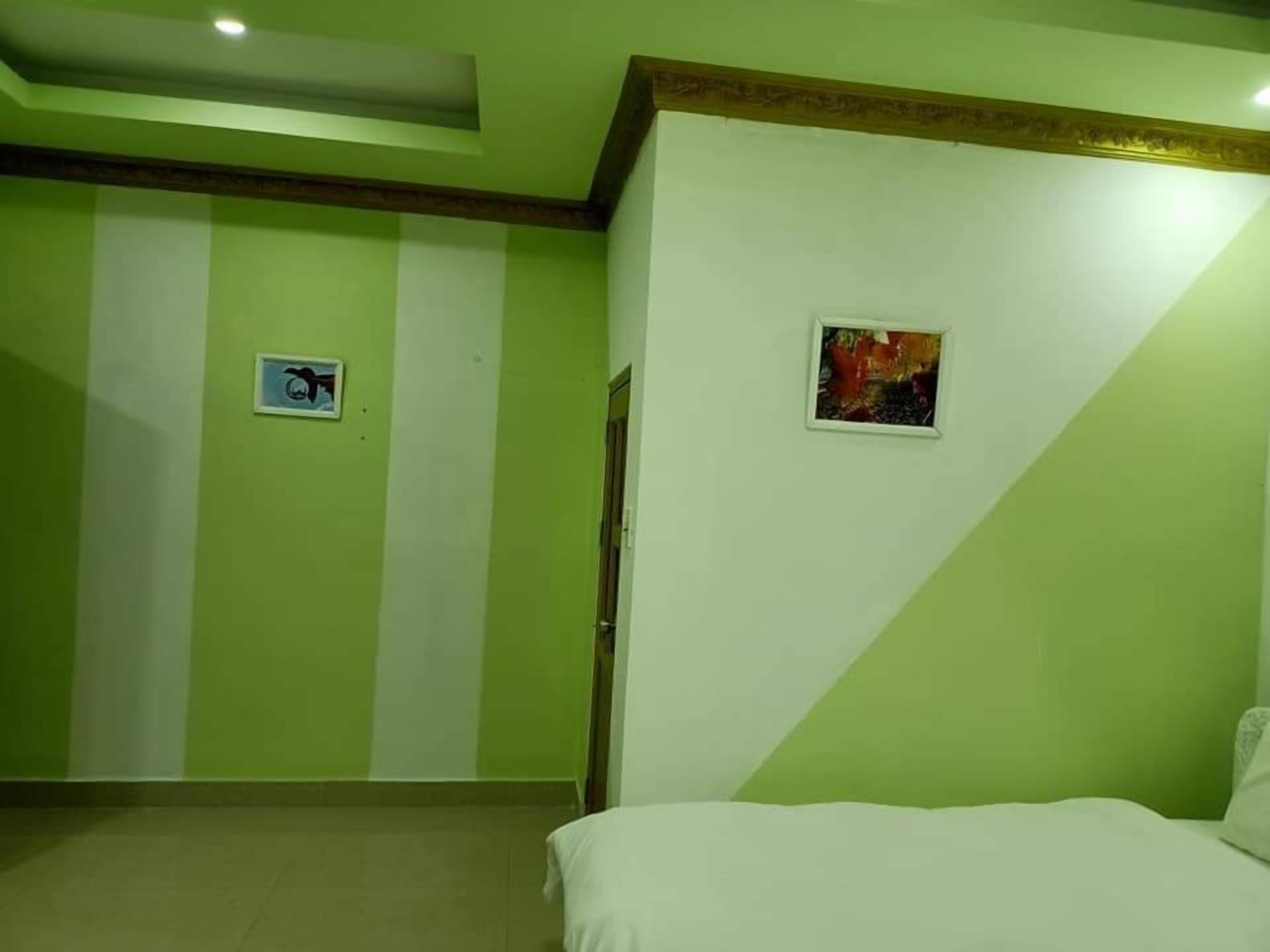 A room with a bed, a door, and a wall with a picture frame.