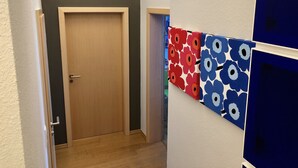 Ein Flur mit einer Holztür, einer Wand mit bunten Blumenmustern und einem weißen Wandabschnitt in Blau.