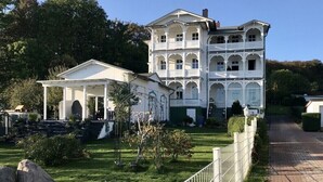Ein großes, weißes, mehrstöckiges Gebäude mit einem zentralen Pavillon und mehreren Balkonen.