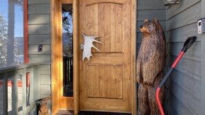 Una puerta de madera con un grabado de oso, un farolillo y una manguera roja en el porche.
