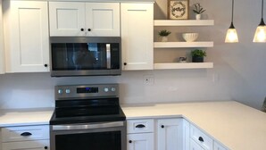 A modern kitchen with white cabinets, a stainless steel oven, a microwave, and pendant lights. - 💗☀️🌊Family Fun In The Sun🌊☀️💗 - 3 BR, 3.5 BA & Pet Friendly Townhouse (Little River)