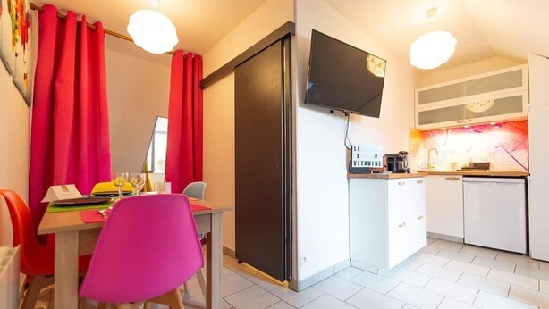 Una cocina compacta con refrigerador, microondas y una pequeña zona de comedor con mesa y sillas.
