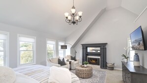 A spacious bedroom with a large bed, a fireplace, a sofa, and a dining area. - 3813 Point Break ~ Walk to Lover's Point Beach! (Pacific Grove)