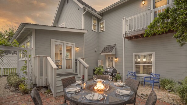 A patio with a round table set for dining, surrounded by wicker chairs. - 3813 Point Break ~ Walk to Lover's Point Beach! (Pacific Grove)
