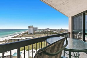 Ein Balkon mit Blick auf den Strand und den Ozean, inklusive Tisch und Stühlen.