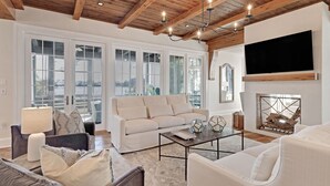 A spacious living room with a large sofa, a coffee table, and a fireplace. - Sea la Vie - Luxury Carillon Beach Home - Lake Views! (Panama City Beach)