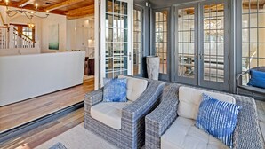A spacious living area with wicker furniture, a ceiling fan, and large sliding glass doors leading to an outdoor patio. - Sea la Vie - Luxury Carillon Beach Home - Lake Views! (Panama City Beach)