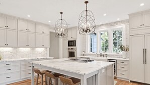 A spacious kitchen with a large island, white cabinetry, and a stone backsplash. - Sea la Vie - Luxury Carillon Beach Home - Lake Views! (Panama City Beach)