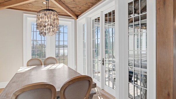 A dining area with a wooden ceiling, large windows, and a chandelier. - Sea la Vie - Luxury Carillon Beach Home - Lake Views! (Panama City Beach)