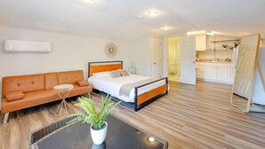 Un dormitorio moderno con cama, sofá, una mesita y una planta en maceta.
