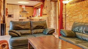 A cozy living room with a leather sofa, a wooden coffee table, and a kitchen in the background.