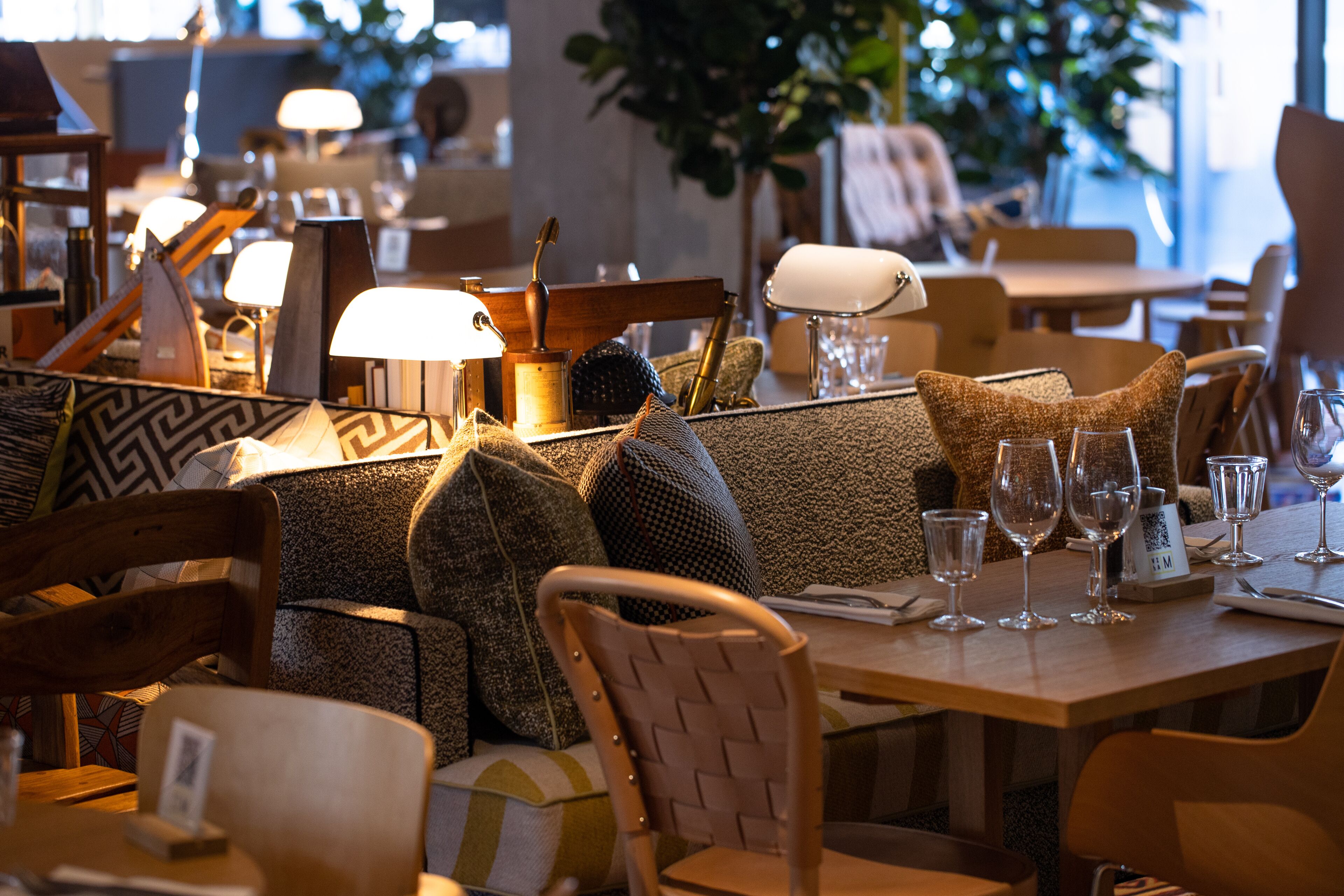 Een restaurantinterieur met houten tafels, zachte zitplaatsen en divers servies.