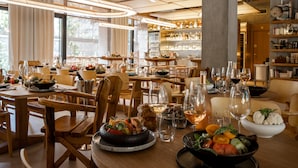 A restaurant with multiple dining tables, chairs, and a variety of dishes and drinks. - Villa M (Paris)