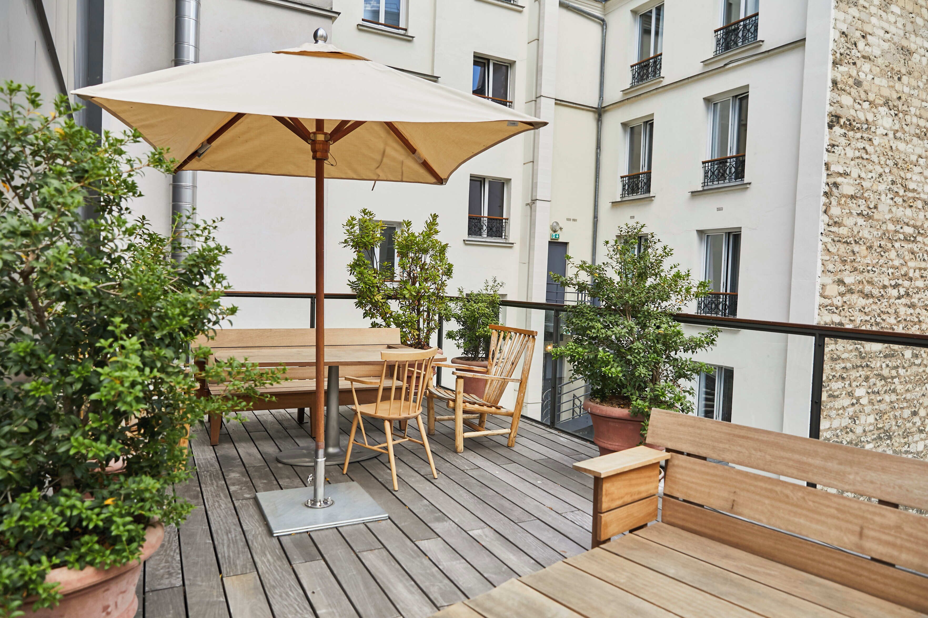 Eine Holzterrasse mit Tisch, Stühlen und einem Sitzplatz, zusätzlich mit Kübelpflanzen.