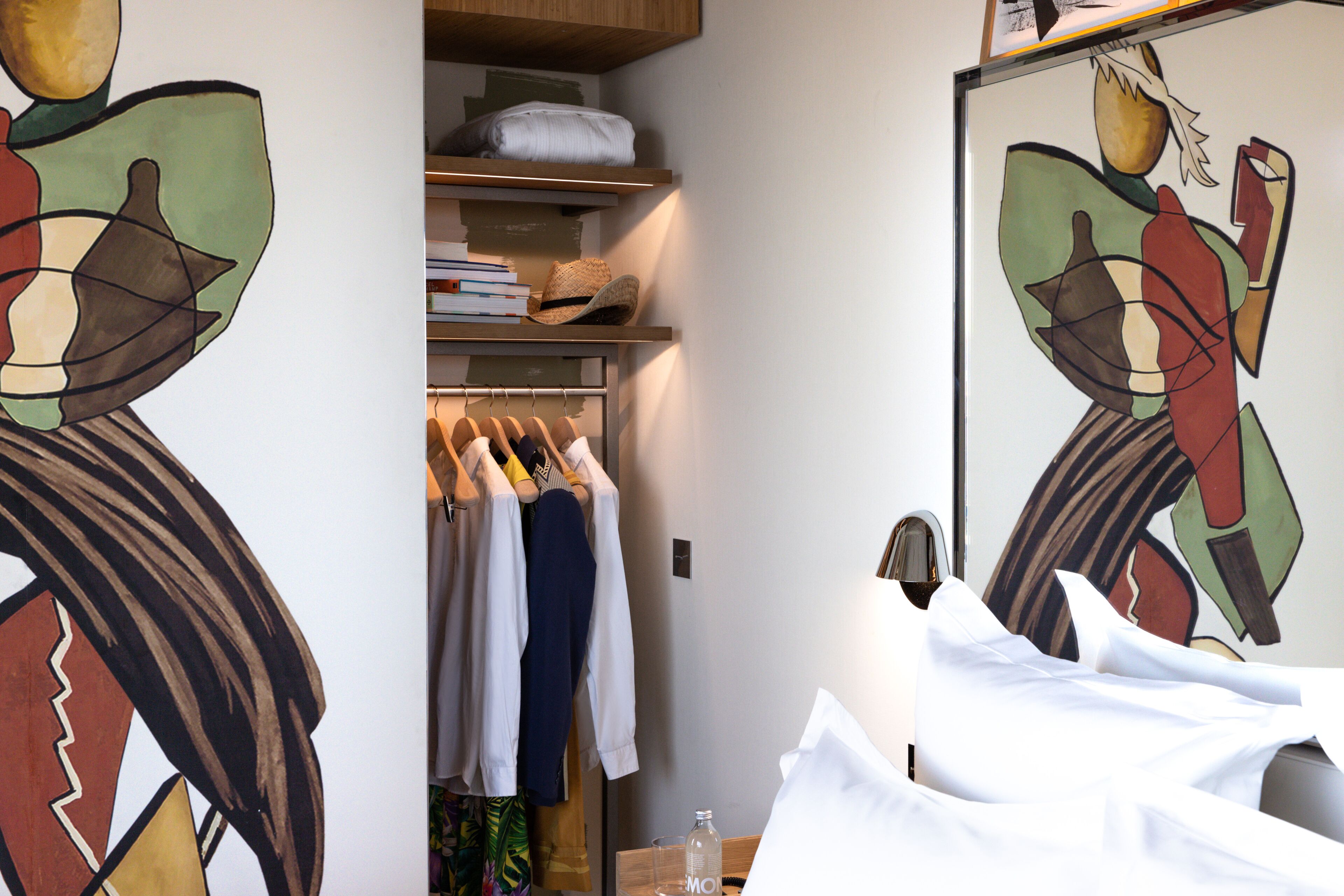 A hotel room with a bed, a wardrobe, and a mirror.
