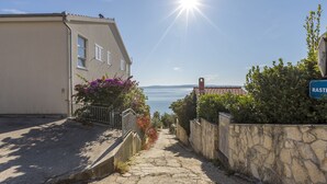 A narrow stone pathway leading to a coastal area with a clear view of the sea. - Charming apart.sa Terasom,250m od Mora,Parking,Wi-Fi,Roštilj,4 zvjezdice**** (Okrug Gornji)