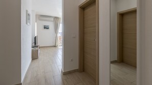 A hallway with a wooden door, a television on a stand, and a window with curtains. - Charming apart.sa Terasom,250m od Mora,Parking,Wi-Fi,Roštilj,4 zvjezdice**** (Okrug Gornji)