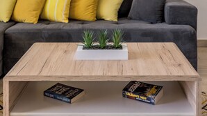 A living room with a grey sofa, yellow cushions, a wooden coffee table with two books, and a painting of a lighthouse on the wall. - Charming apart.sa Terasom,250m od Mora,Parking,Wi-Fi,Roštilj,4 zvjezdice**** (Okrug Gornji)