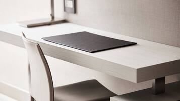 A modern, minimalist desk with a sleek, light-colored wood finish and a black tablet on it.