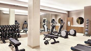 A gym with exercise equipment, including treadmills, elliptical machines, and dumbbells.