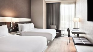 Una habitación de hotel con dos camas, un escritorio, una silla y un banco.