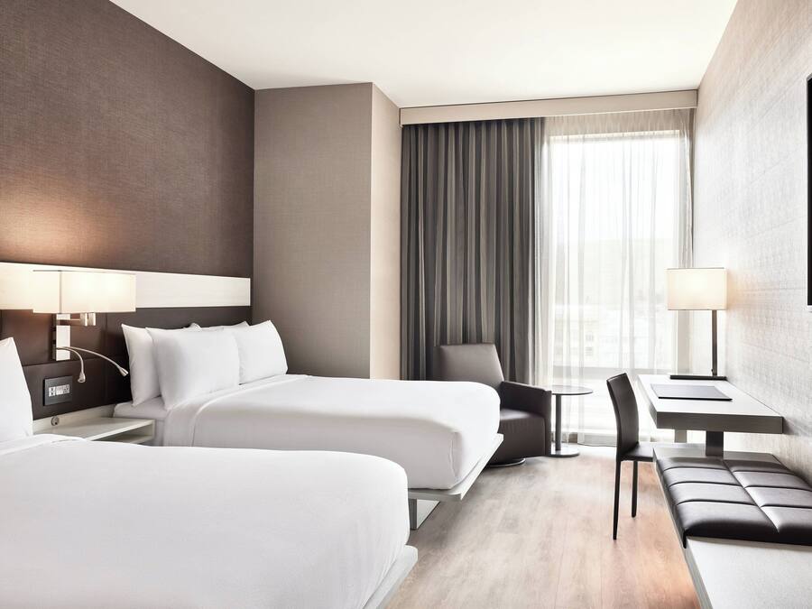 Een hotelkamer met twee bedden, een bureau, een stoel en een bank.