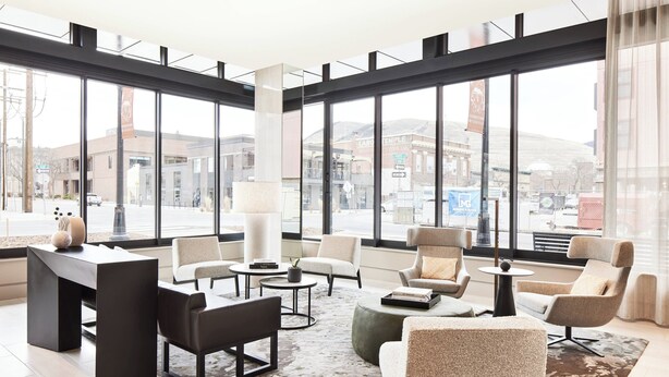 Un moderno vestíbulo de hotel con amplios ventanales, una recepción, asientos cómodos y vistas a la ciudad.