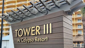 A sign for Tower III at Calypso Resort, featuring a modern design with a wooden facade and metal accents. - Flip Flop at Calypso III. Luxury, view, location and amenities. Sleeps 9 (Panama City Beach)