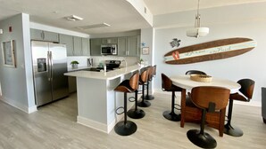 A modern kitchen with a central island, stainless steel appliances, and a dining area with bar stools. - Flip Flop at Calypso III. Luxury, view, location and amenities. Sleeps 9 (Panama City Beach)