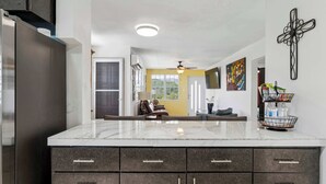 A modern kitchen with a marble countertop, dark cabinetry, and a ceiling fan. - 3 Villas with Ocean Views & 2 Private Pools (Luquillo)