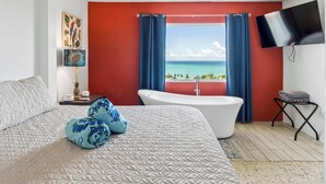 A bedroom with a bed, a bathtub, a TV, and a view of the ocean. - 3 Villas with Ocean Views & 2 Private Pools (Luquillo)