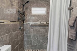 A bathroom with a shower, a toilet, and a towel rack.