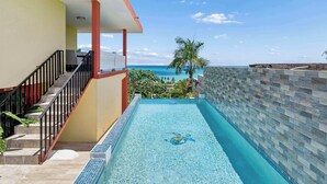 A swimming pool with a clear view of the ocean, a staircase, and a tiled wall. - 3 Villas with Ocean Views & 2 Private Pools (Luquillo)