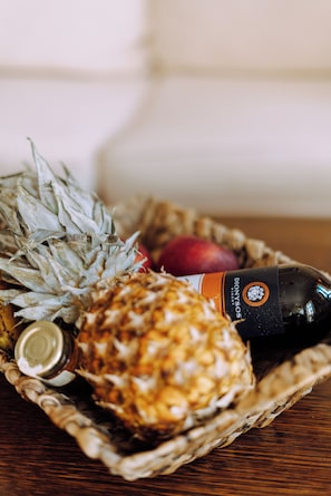 A basket containing a pineapple, an apple, and a bottle of drink. - Lithostroto Suites (Kefalonia)
