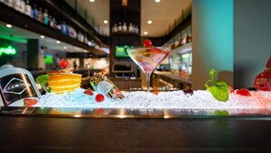 Een bar met een martini glas, ijs en diverse soorten fruit.