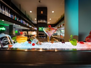 Een bar met een martini glas, ijs en diverse soorten fruit.