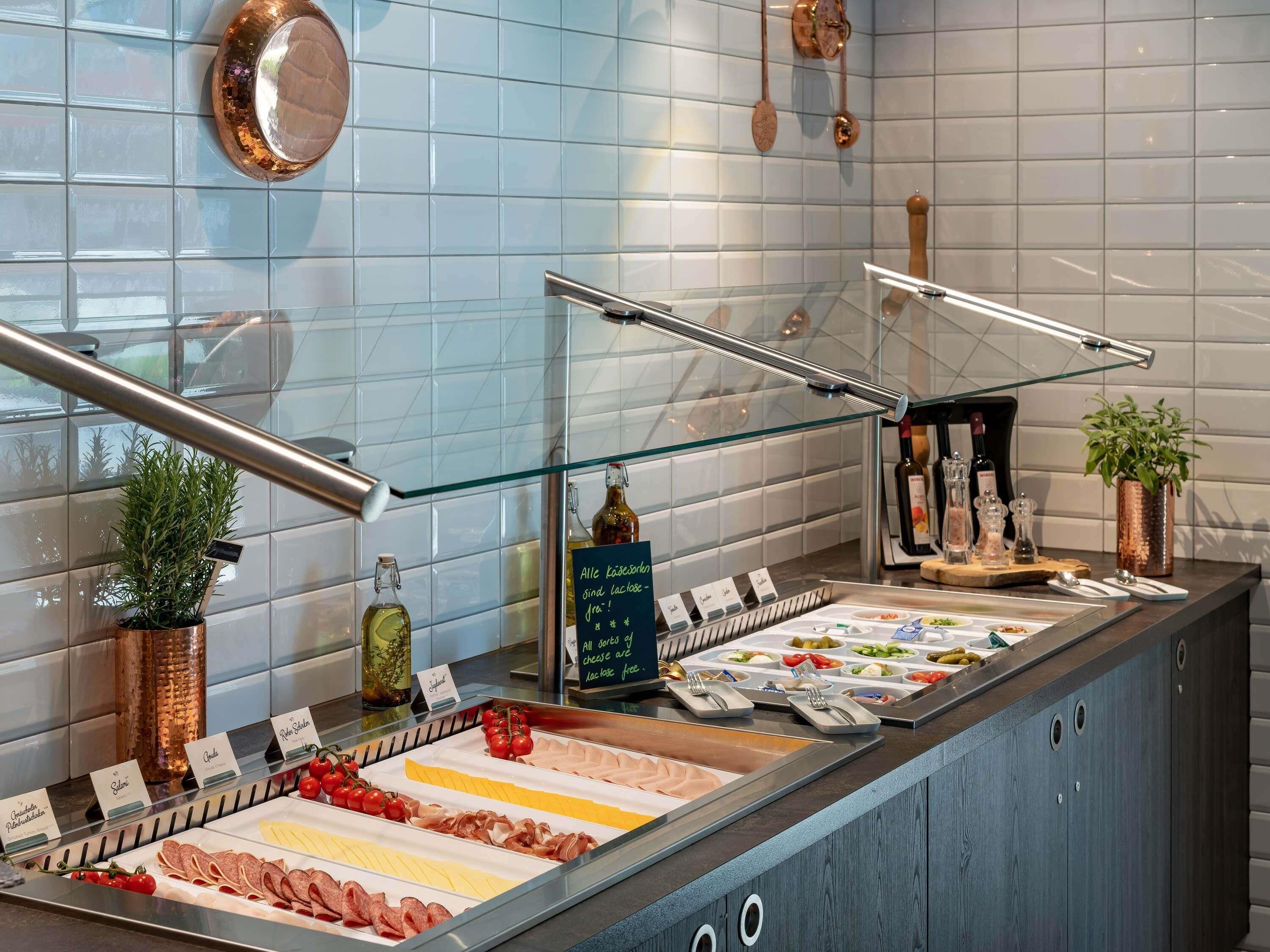 A buffet area with various food options, including meats, cheeses, and salads, displayed in a glass-fronted case.