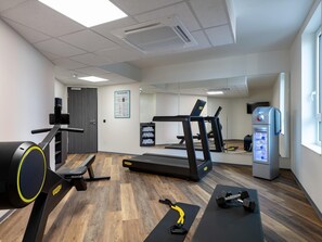 Ein Fitnessraum mit Trainingsgeräten, Laufband und Wasserspender.