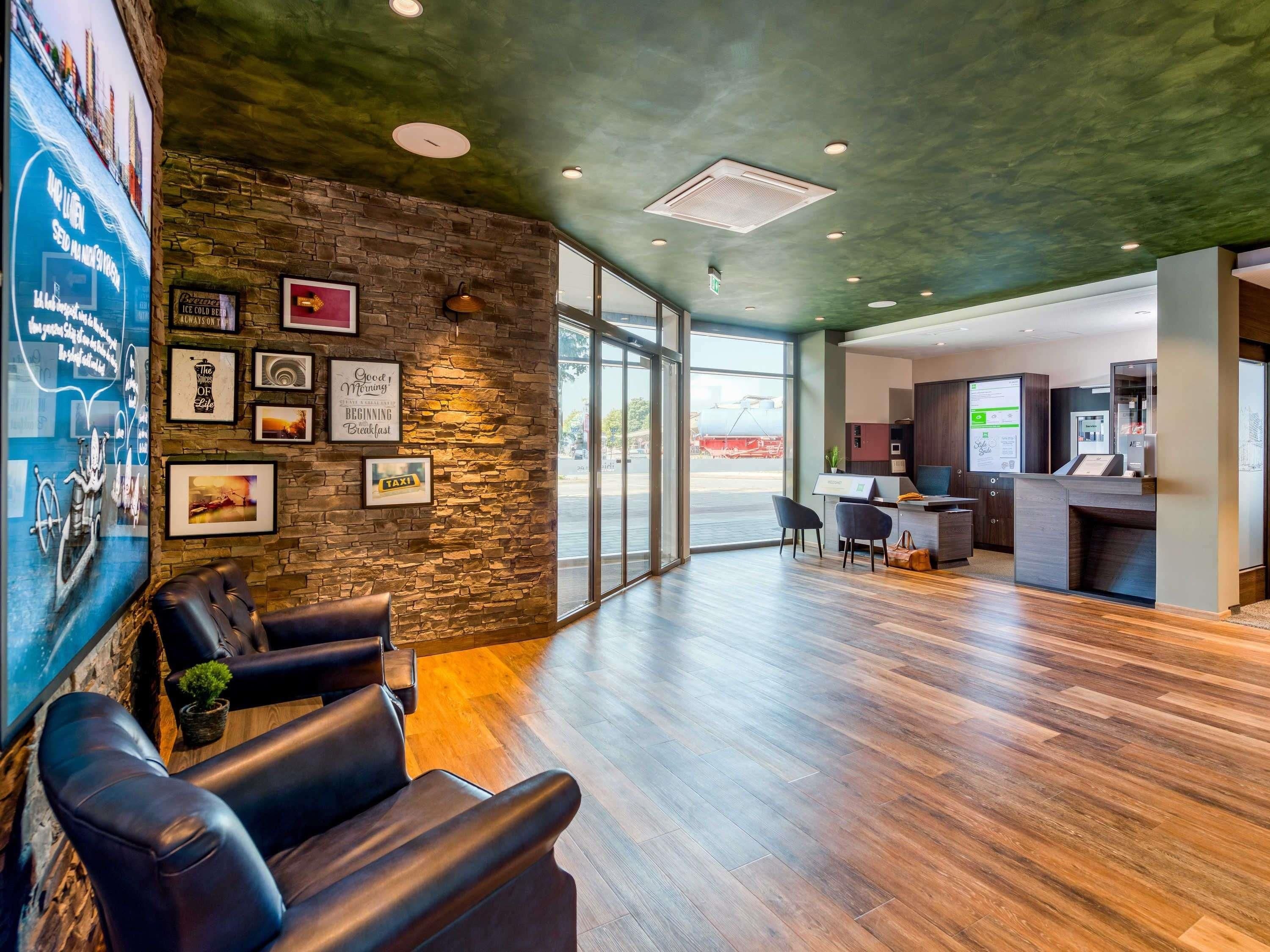 A modern reception area with a stone wall, leather seating, a reception desk, and a view of the outside.