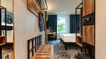 Une chambre d’hôtel compacte comprenant un lit superposé, un bureau, une chaise et une petite table.