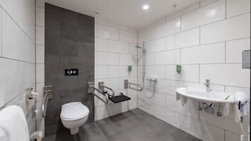 A modern bathroom with a toilet, a sink, a shower, and a grab bar.