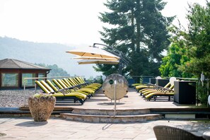 Un espace aménagé au bord de la piscine, avec des chaises longues, des parasols et une sculpture métallique décorative.