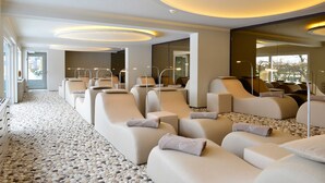 A modern spa room with multiple reclining chairs, a pebbled floor, and a large mirror. - Junior Suite - Hotel Freund (Vöhl)