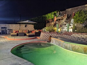 A backyard with a swimming pool, outdoor seating, and a stone wall. - Huge Desert Oasis w Pool+Spa. Sleeps 12. Centrally located to all of Ch Valley (Desert Hot Springs)